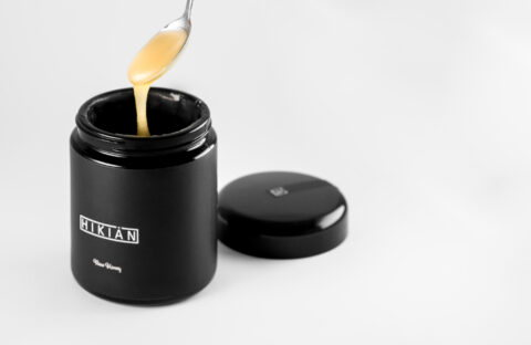 open honey jar with honey dripping from the spoon