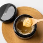 open honey jar and honey on a spoon