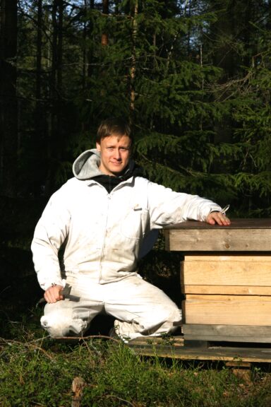beekeeper sitting by the beehive